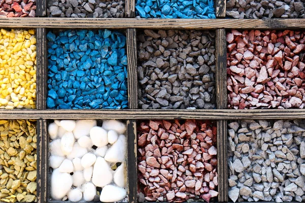 Veel verschillende kleuren stenen in houten kisten als achtergrond — Stockfoto