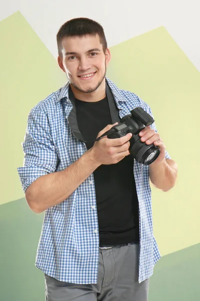 Young photographer with camera on color background — Stock Photo, Image