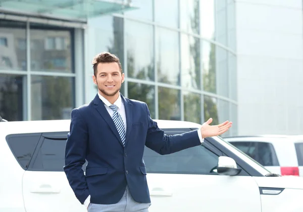 Sprzedawca, stojący w pobliżu nowego samochodu na zewnątrz. — Zdjęcie stockowe