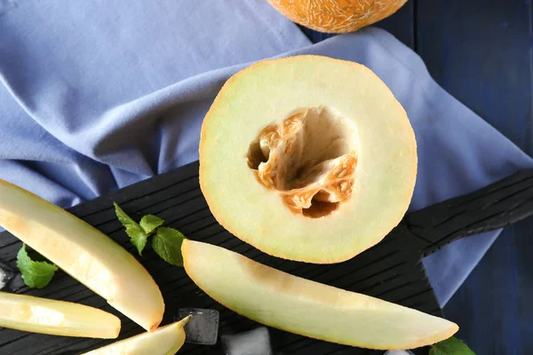 Brett mit geschnittener leckerer Melone auf Holztisch — Stockfoto