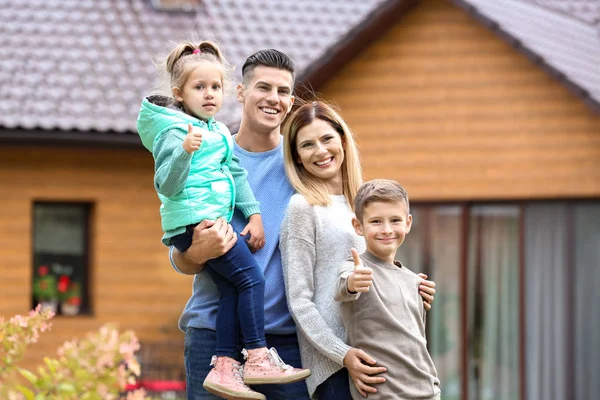 Lycklig familj står nära deras hus — Stockfoto