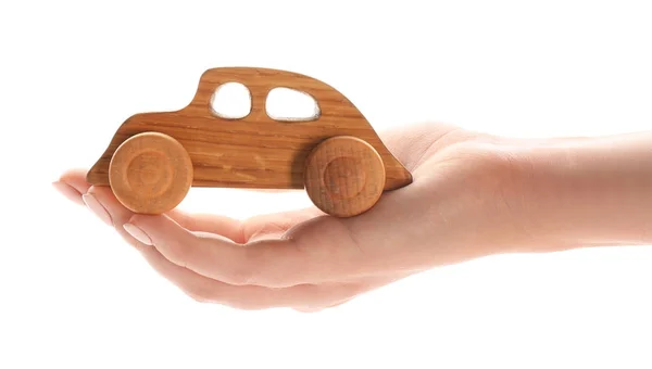 Γυναικείο χέρι με ξύλινο αυτοκίνητο σε λευκό φόντο — Φωτογραφία Αρχείου