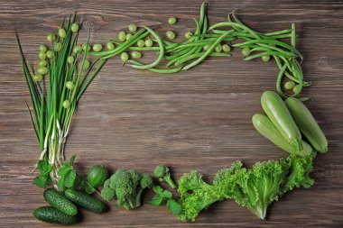 Ahşap arka plan üzerinde farklı yeşil sebze ve meyve ile kompozisyon