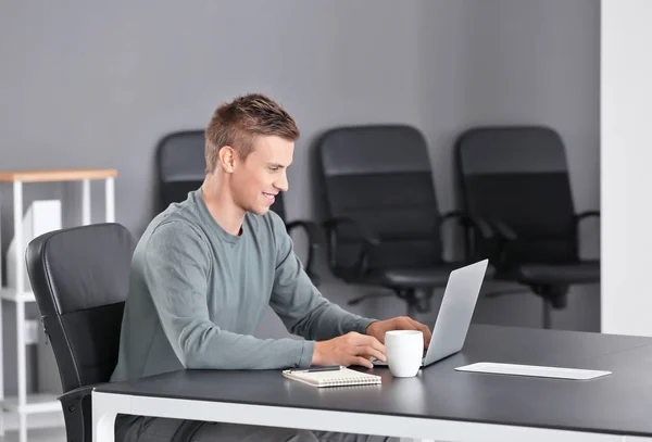 Bel homme avec ordinateur portable au bureau — Photo