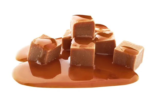 Deliciosos caramelos con salsa de caramelo sobre fondo blanco — Foto de Stock