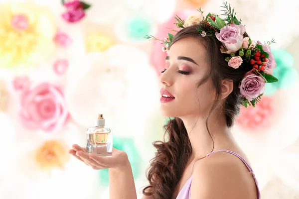 Mooie jonge vrouw met fles van bloemen parfum op kleur achtergrond — Stockfoto