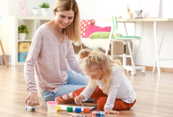 Mother with cute girl painting picture on sheet of paper, indoors — Stock Photo, Image