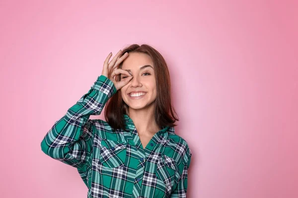 Smuk smilende kvinde viser OK gestus på farve baggrund - Stock-foto