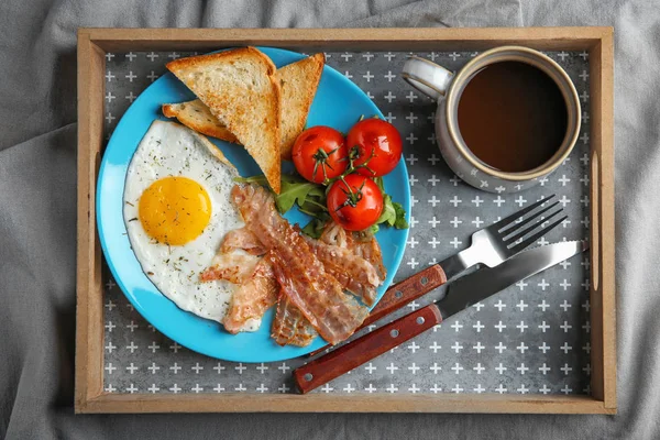 Тарелка с яичницей, беконом и помидорами на подносе — стоковое фото