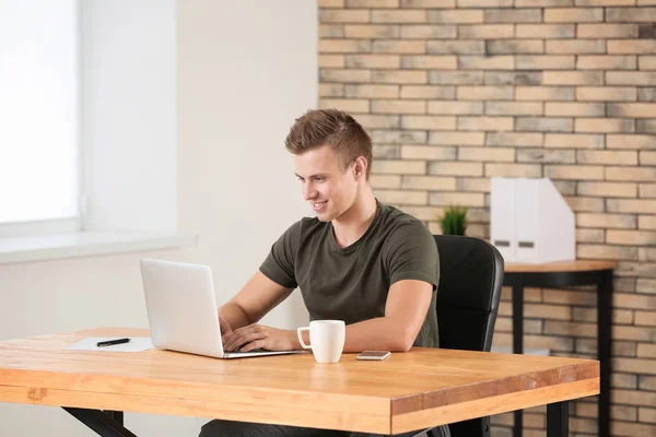 Bel homme avec ordinateur portable au bureau — Photo