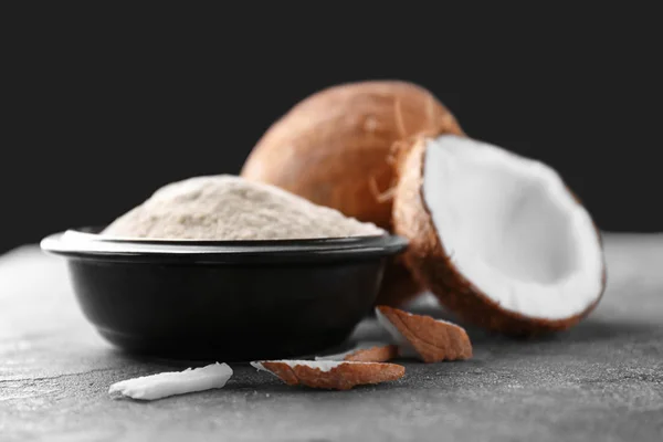 Миска с кокосовой мукой и свежими орехами на столе — стоковое фото