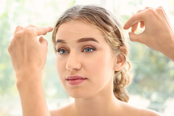 Mujer joven que tiene procedimiento de corrección de cejas en el salón de belleza —  Fotos de Stock