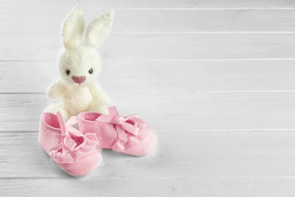 Baby's first bootees and toy on wooden table — Stock Photo, Image