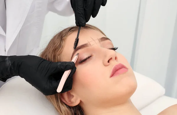 Mujer joven que tiene procedimiento de corrección de cejas en el salón de belleza — Foto de Stock