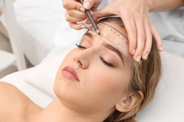 Mujer joven que tiene procedimiento de corrección de cejas en el salón de belleza —  Fotos de Stock