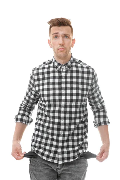Sad young man showing his empty pockets on white background — Stock Photo, Image