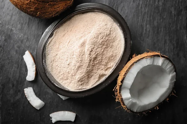 Tigela com farinha de coco e nozes frescas na mesa — Fotografia de Stock