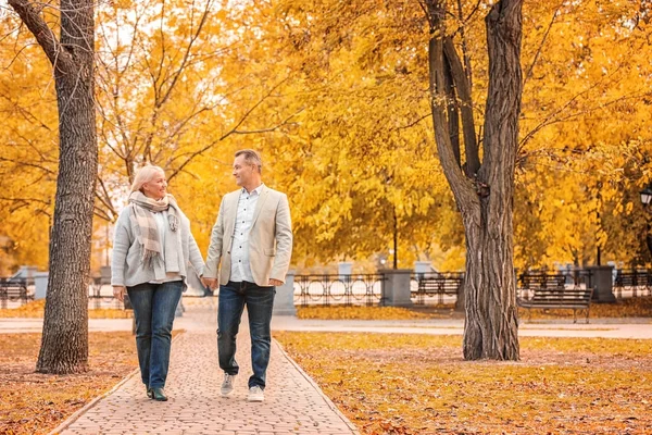 Зрелая пара, гуляющая в парке в осенний день — стоковое фото