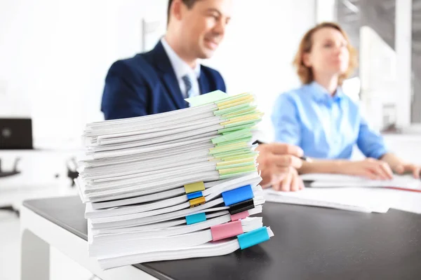 Empilhamento de documentos na mesa e trabalhadores desfocados no escritório — Fotografia de Stock