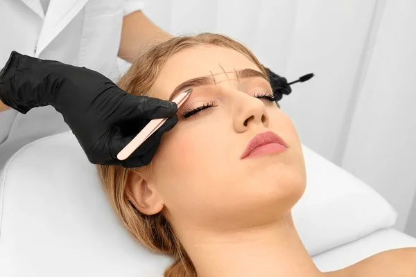 Mujer joven que tiene procedimiento de corrección de cejas en el salón de belleza — Foto de Stock