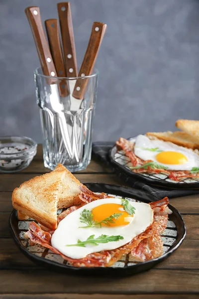 Plaat met gebakken ei en spek op houten tafel — Stockfoto