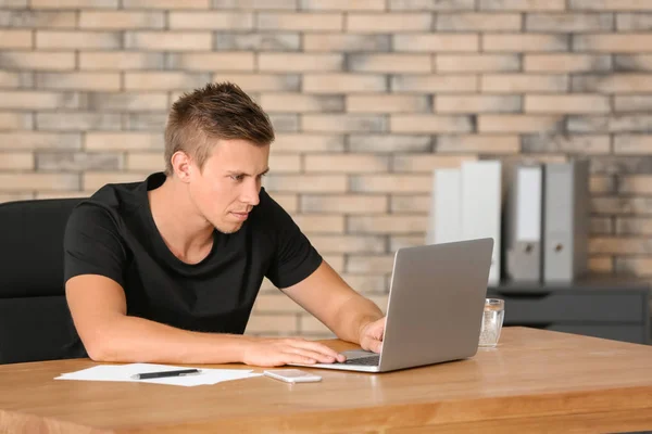 Bel homme avec ordinateur portable au bureau — Photo