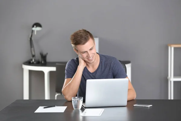 Bel homme avec ordinateur portable au bureau — Photo