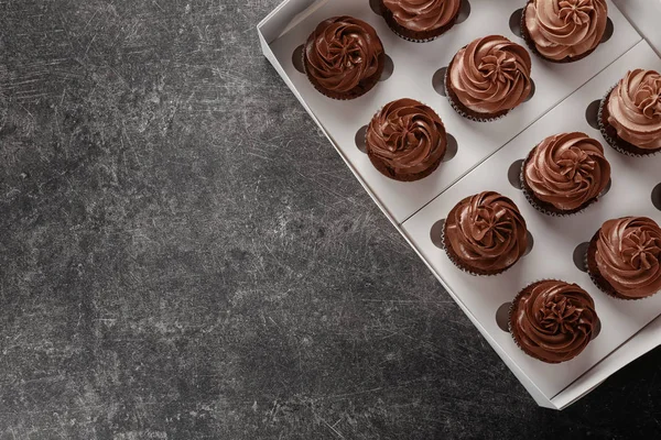 Boîte en carton avec de délicieux cupcakes au chocolat sur fond gris — Photo