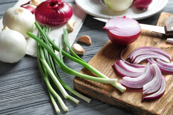 Samenstelling met verschillende uien op houten tafel — Stockfoto