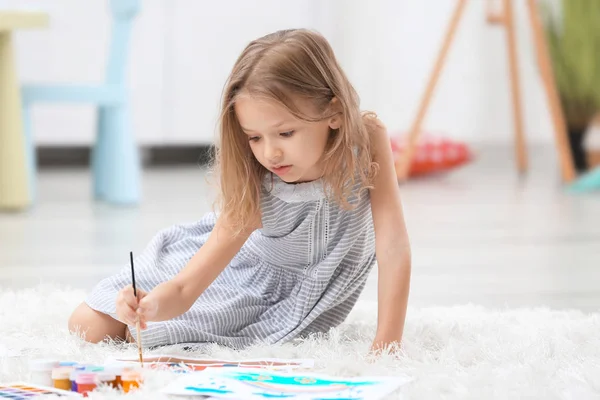 Niña pintando mientras está sentada en el suelo en casa —  Fotos de Stock