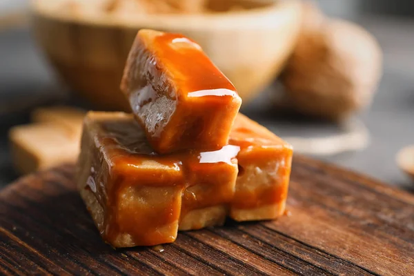 Pyszne cukierki z sosem karmelowym, płyty drewniane — Zdjęcie stockowe