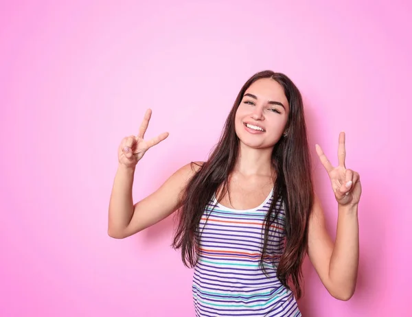 Bella donna sorridente che mostra il gesto della vittoria sullo sfondo a colori — Foto Stock