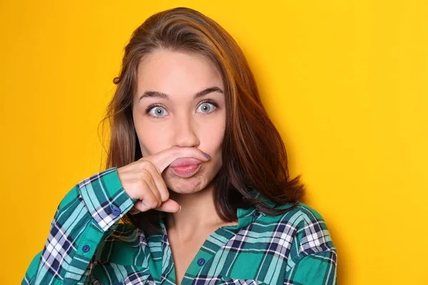 Jeune femme avec grimace drôle sur fond de couleur — Photo