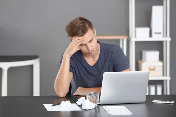 Trött man med laptop i office — Stockfoto