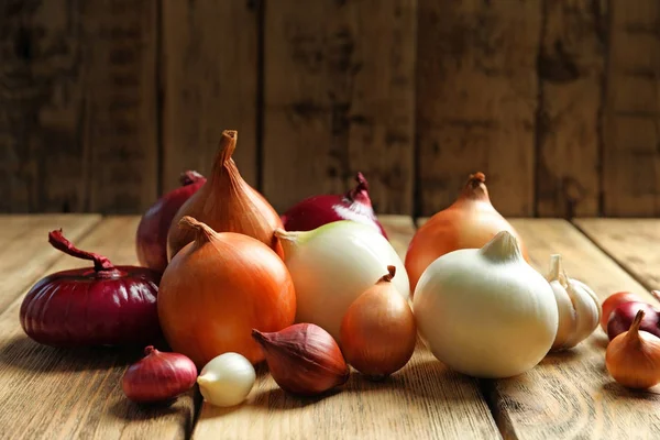 Verscheidenheid van verschillende uien op houten tafel — Stockfoto