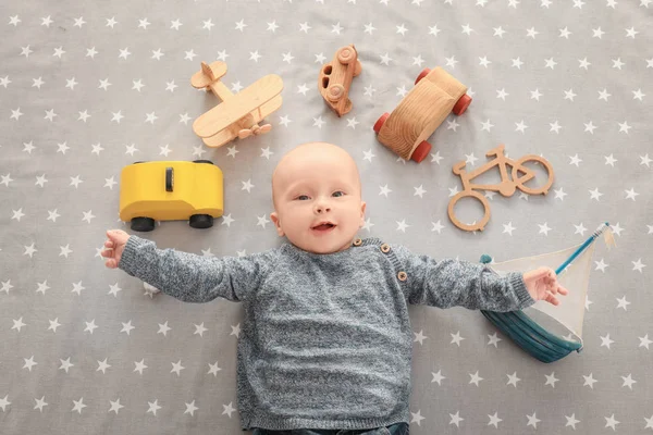 Lindo chico con juguetes en la sábana — Foto de Stock