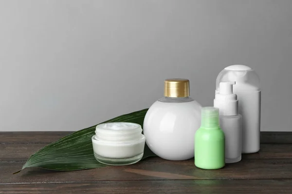 Set of body care products on wooden table against grey background
