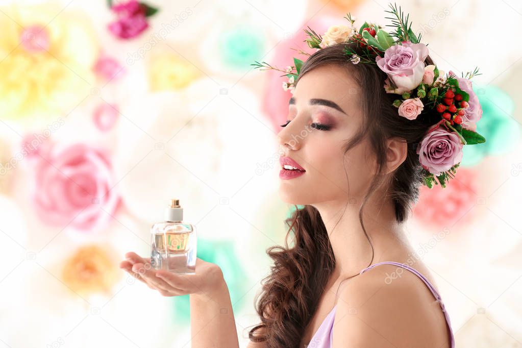 Beautiful young woman with bottle of floral perfume on color background