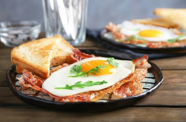 Sahanda yumurta ve domuz pastırması ahşap masa üzerinde plaka