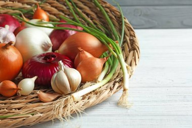 Hasır tepsi ahşap masa üzerinde farklı soğan ile
