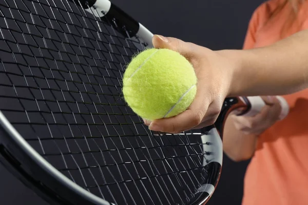 Woman with tennis racket and ball on dark grey background — Stock Photo, Image