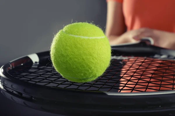 Жінка з тенісною ракеткою і м'ячем на темно-сірому фоні, крупним планом — стокове фото