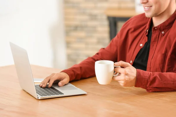 Человек пьет кофе во время использования ноутбука в офисе — стоковое фото