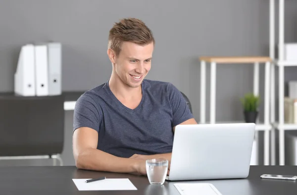 Knappe man met laptop op kantoor — Stockfoto