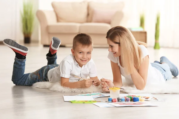 Mãe com foto de pintura bonito menino na folha de papel, dentro de casa — Fotografia de Stock