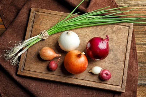 Variété d'oignons différents sur planche de bois — Photo