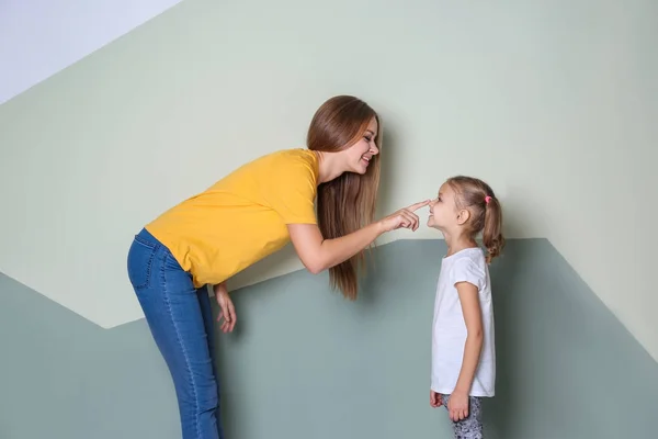 Mãe feliz e sua filha contra a parede de cor na sala de crianças — Fotografia de Stock