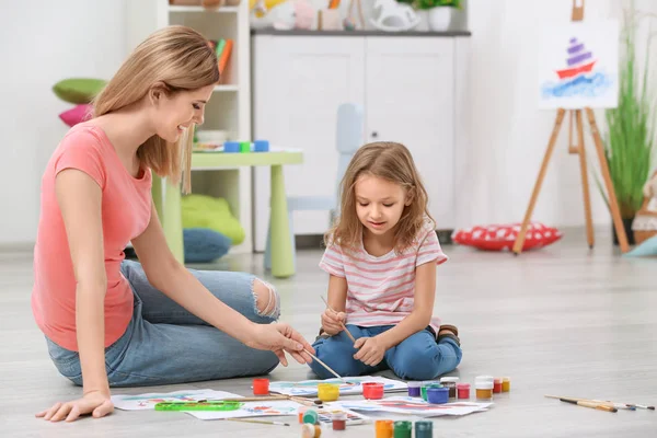 Мать с дочерью рисуют, сидя дома на полу — стоковое фото