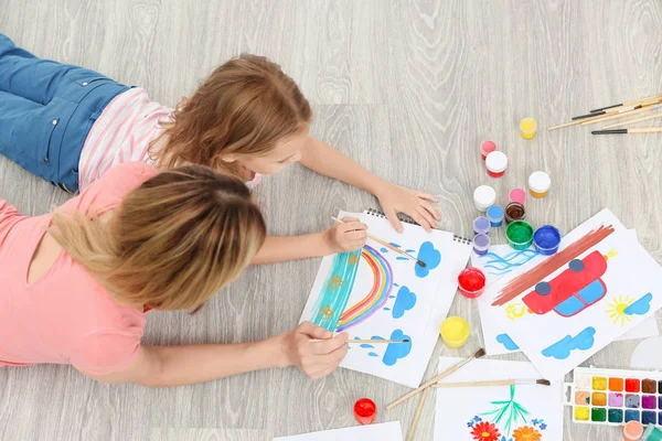 Mutter mit Tochter malt, während sie zu Hause auf dem Boden liegt — Stockfoto