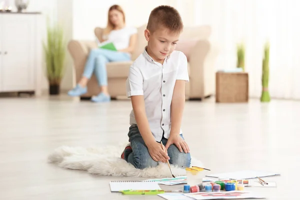 Cute boy painting picture on sheet of paper, indoors